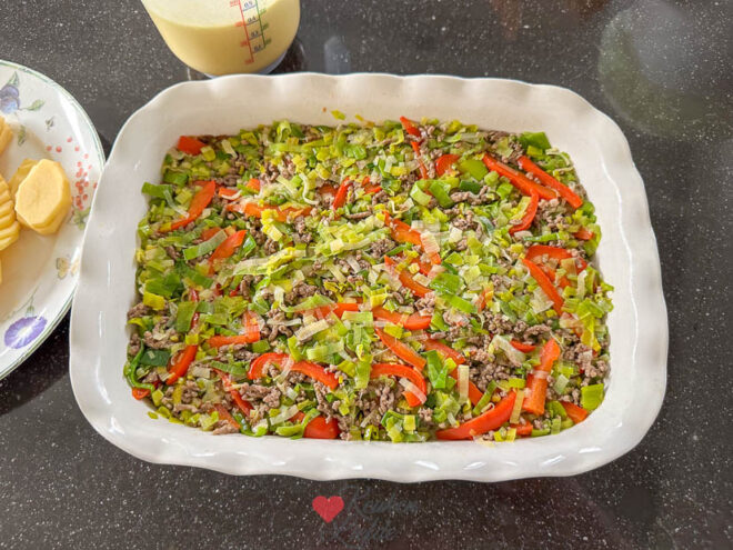 Verdeel de helft van de aardappelschijfjes en het gehakt-groentemengsel over de ovenschaal