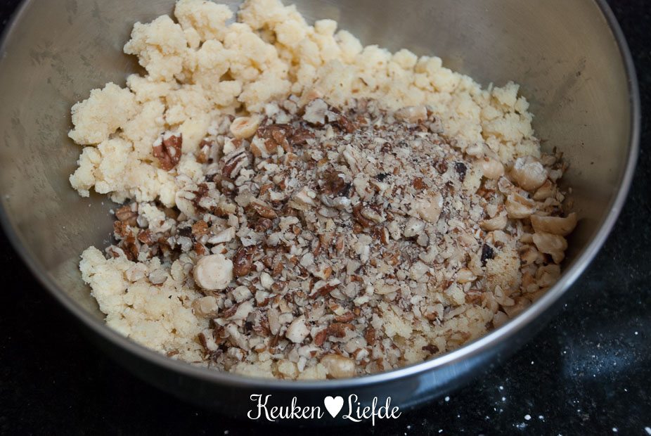 Roer de noten door het kruimeldeeg